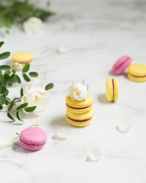 Bitterkoekjes en bloemen Frans eten Gele en roze bitterkoekjes op een marmeren tafel Frans dessert