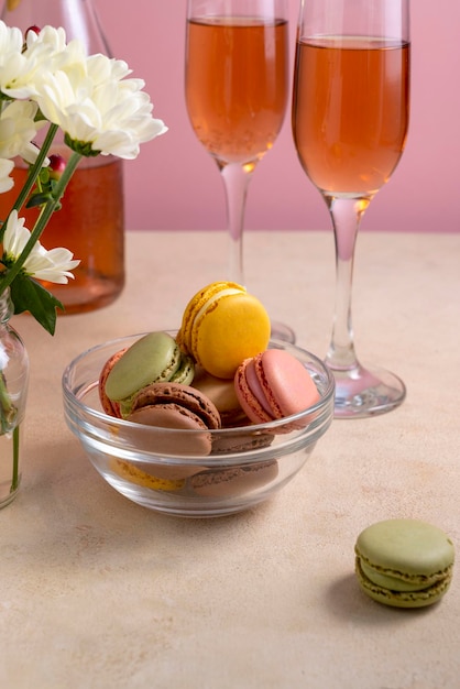 Bitterkoekjes kleurrijke koekjes in glazen kom geserveerd met champagne drinken Macarons frans zoet dessert roze achtergrond