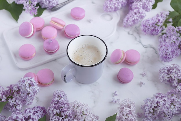 Bitterkoekjes met koffie op een marmeren achtergrond met lila bloemen, Lichte achtergrond, Zoetwaren in een blogger-stijl