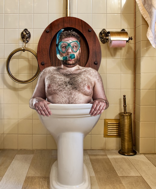 Bizarre man with goggles swimming in vintage toilet