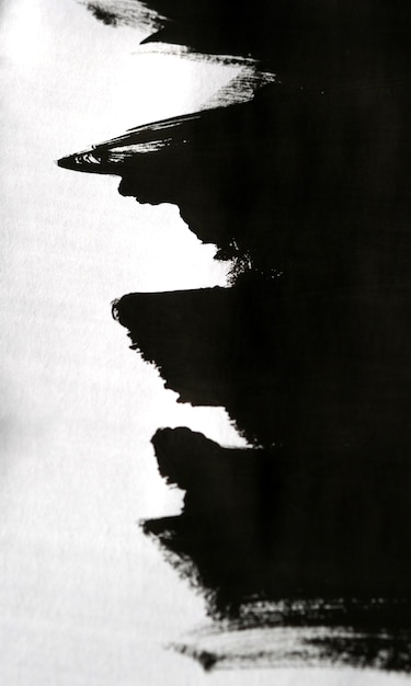 片手で分離された白い紙の上の黒い抽象的な即興のブラシストローク