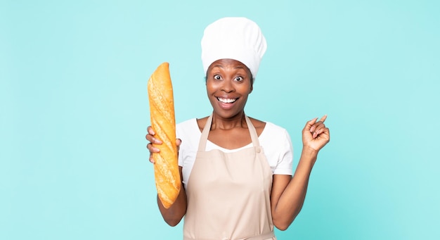 빵 바게트를 들고 흑인 아프리카계 미국인 성인 요리사 여자