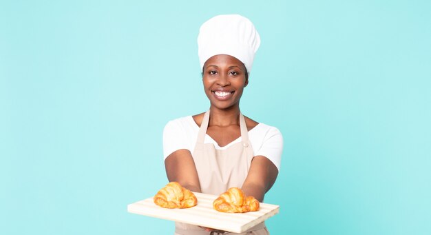 Black african american adult chef woman holding a croissants tray