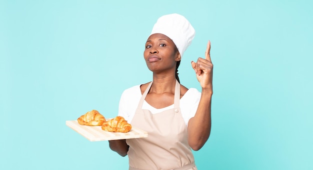 Black african american adult chef woman holding a croissants tray