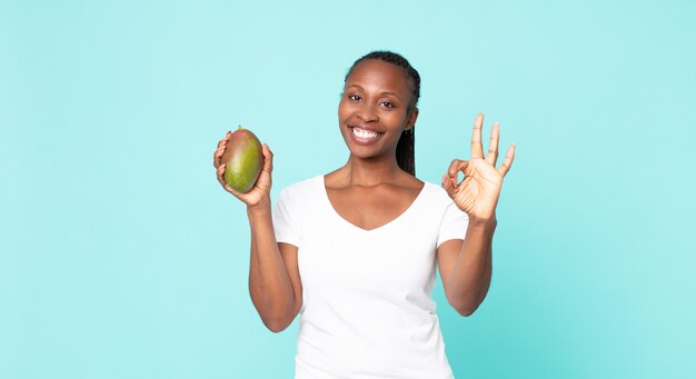 Black african american adult woman holding a mango fruit