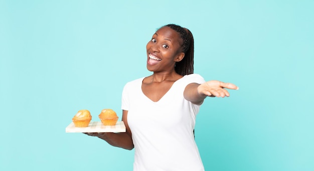 black african american adult woman holding a muffins tray