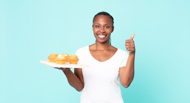 Donna adulta afroamericana nera che tiene un vassoio di muffin