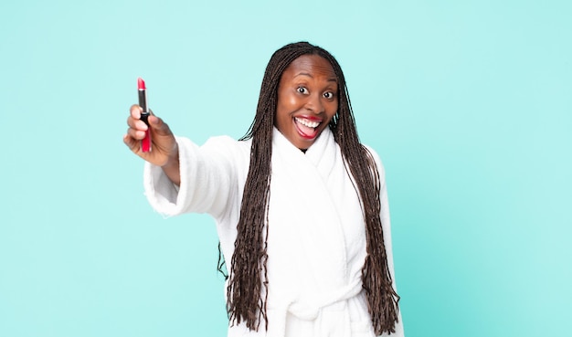 Black african american adult woman wearing bathrobe and holding a lipstick