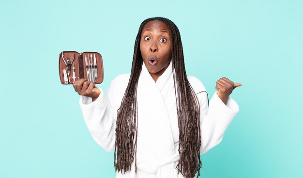 Black african american adult woman wearing bathrobe and holding
a make up bag with nains tools