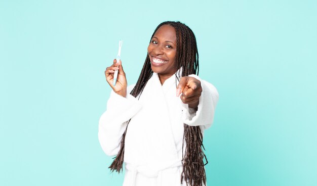 Black african american adult woman wearing bathrobe and holding a teeth brush