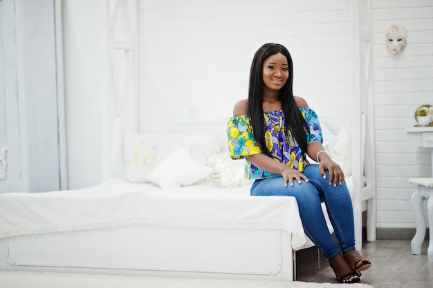 Black african american millennial girl in living room happy dark skinned young woman on weekend at home sitting on the bed