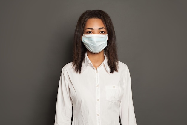 Photo black african american woman wearing a face mask on yellow background woman in medical mack flu epidemic and virus protection concept