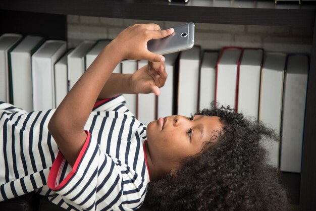 Black african boy playing mobile phone in school.