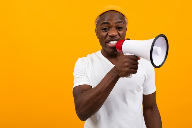 Black african man shouts in a megaphone on yellow