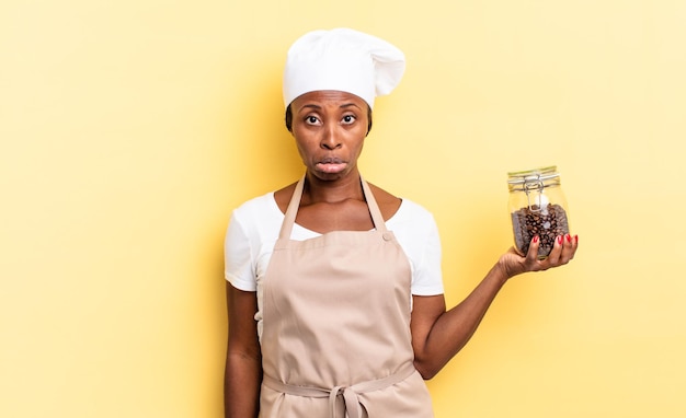 Black afro chef woman feeling sad and whiney with an unhappy look, crying with a negative and frustrated attitude. coffee beans concept