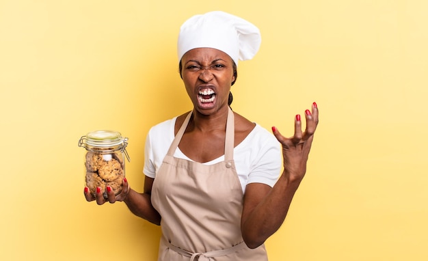 Photo black afro chef woman looking angry, annoyed and frustrated screaming wtf or whatâs wrong with you. cookies concept