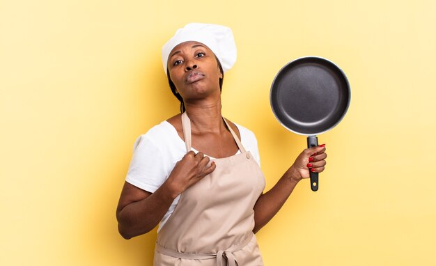 Donna chef afro nera che sembra arrogante, di successo, positiva e orgogliosa, che indica se stessa