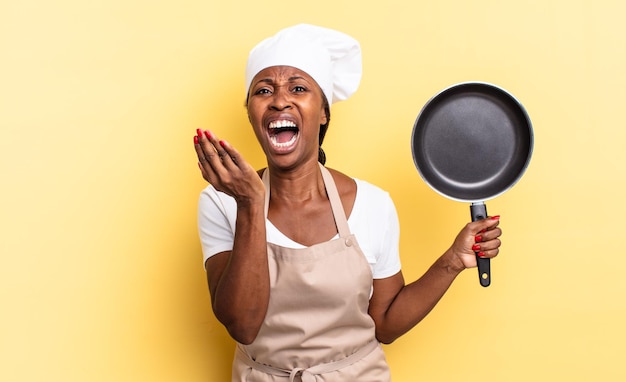 Black afro chef woman looking desperate and frustrated, stressed, unhappy and annoyed, shouting and screaming