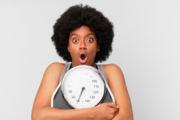 Black afro fitness woman with a balance or scale