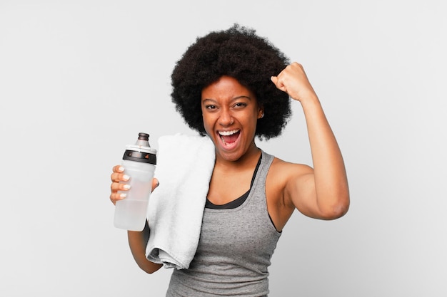 Black afro fitness woman with a towel and water can