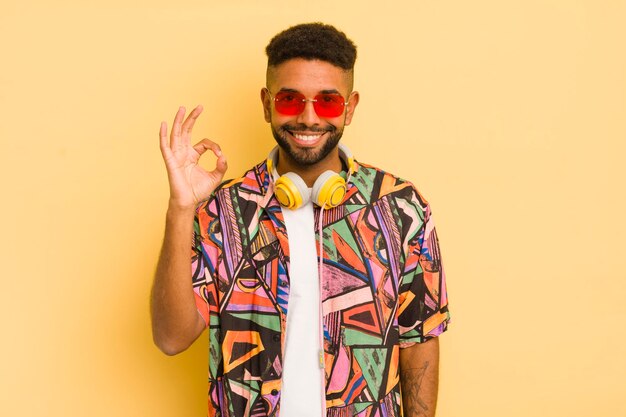 Black afro man feeling happy showing approval with okay gesture sunglasses and headphones concept