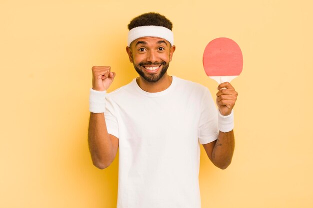 Uomo afro nero che si sente scioccato ridendo e celebrando il concetto di pingpong di successo