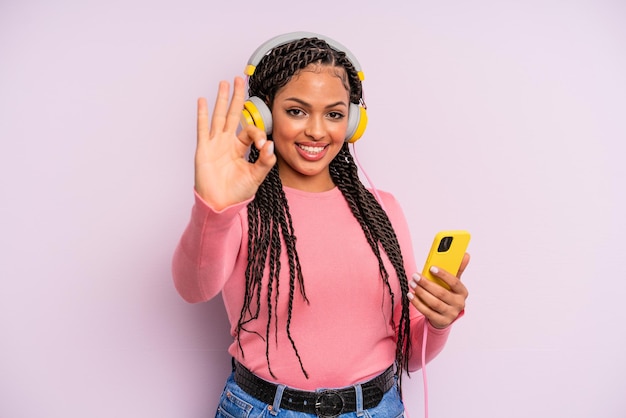 Black afro woman feeling happy, showing approval with okay gesture. listening music concept