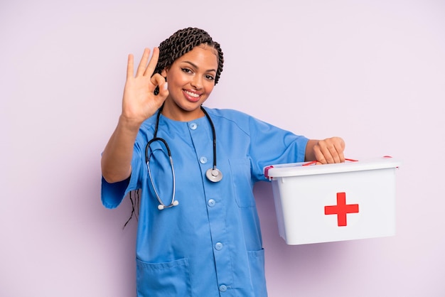черная афро-женщина чувствует себя счастливой, показывая одобрение хорошим жестом. концепция медсестры и аптечки