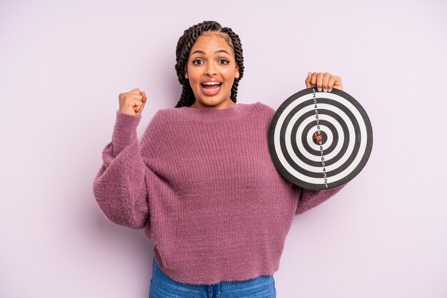 Black afro woman feeling shocked,laughing and celebrating success. target dart concept