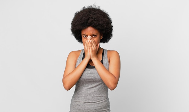 black afro woman feeling worried, hopeful and religious, praying faithfully with palms pressed, begging forgiveness