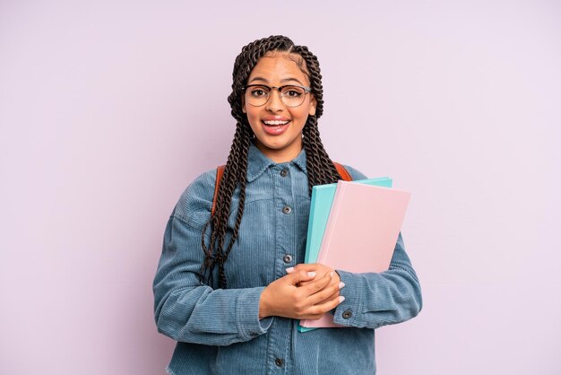 Photo black afro woman looking happy and pleasantly surprised university student concept