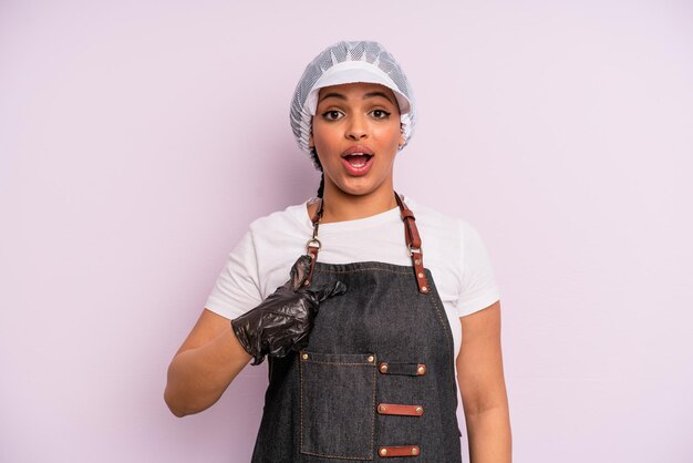 Black afro woman looking shocked and surprised with mouth wide open pointing to self fishmonger concept