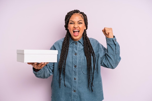 Black afro woman shouting aggressively with an angry expression. packages box concept