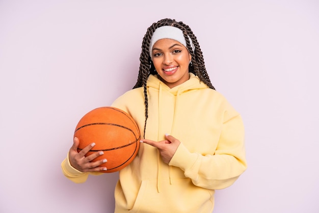Foto donna afro nera che sorride allegramente sentendosi felice e indicando il concetto di basket laterale
