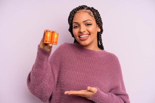 Black afro woman smiling cheerfully feeling happy and showing a concept battery concept