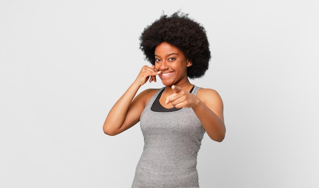 black afro woman smiling cheerfully and pointing to camera while making a call you later gesture, talking on phone