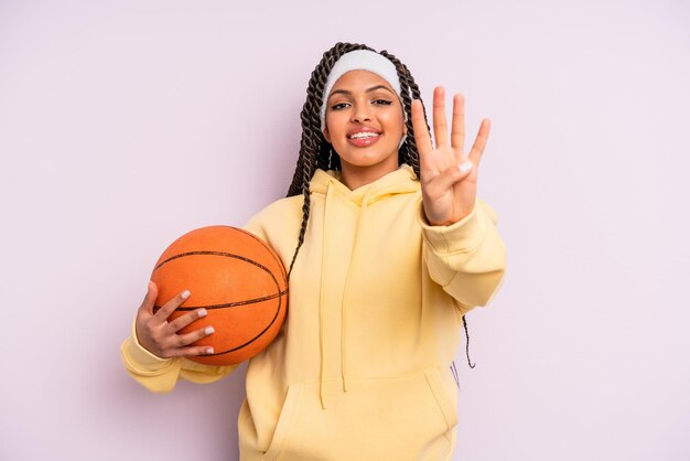 black afro woman smiling and looking friendly, showing number four. basketball concept