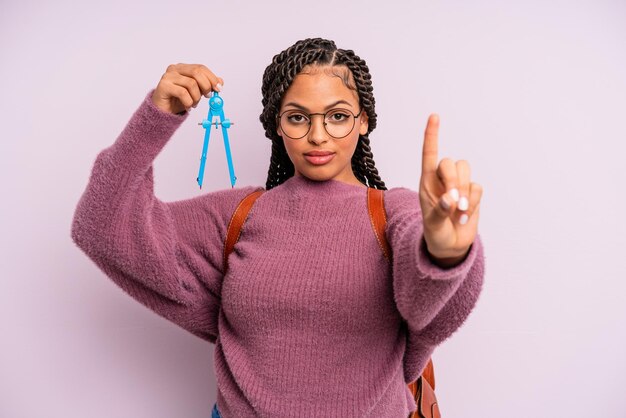 笑顔でフレンドリーに見える黒人のアフロの女性は、ナンバーワンのメジャーコンパス学生の概念を示しています