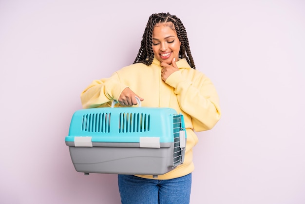 black afro woman smiling with a happy, confident expression with hand on chin. pet travel container concept