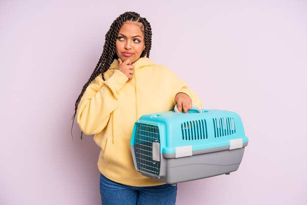 Black afro woman thinking, feeling doubtful and confused. pet travel container concept