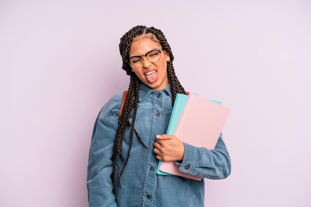 Photo black afro woman with cheerful and rebellious attitude, joking and sticking tongue out. university student concept