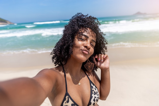 Black afro young cute girl, curly hair, bikini, beach. Afro American summer vacation holiday.