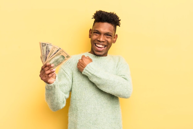 Черный афро молодой человек чувствует себя счастливым и сталкивается с проблемой или празднует концепцию долларовых банкнот