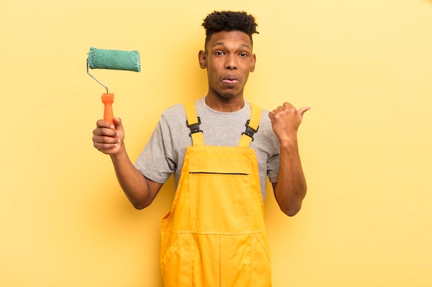 Black afro young man looking astonished in disbelief housekeeper painting home