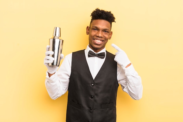 Black afro young man smiling confidently pointing to own broad smile bartender and cocktail concept