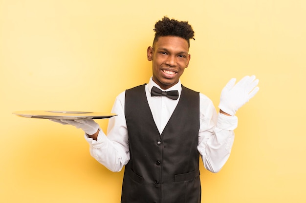 Black afro young man smiling happily waving hand welcoming and greeting you