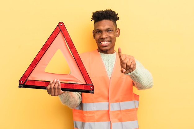 Photo black afro young man smiling proudly and confidently making number one car fault and triangle concept