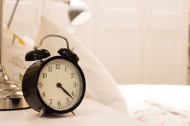 Black alarm clock on the bedside table