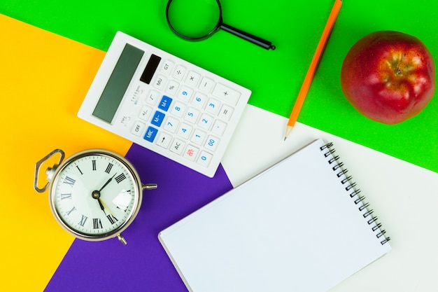 Black alarm clock on color block, office interior