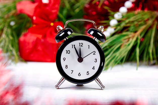 Black Alarm clock and fir tree branch, red christmas decorations